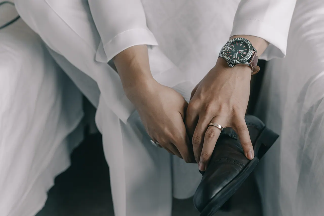The groom’s hands, a watch and his shoes, close up.