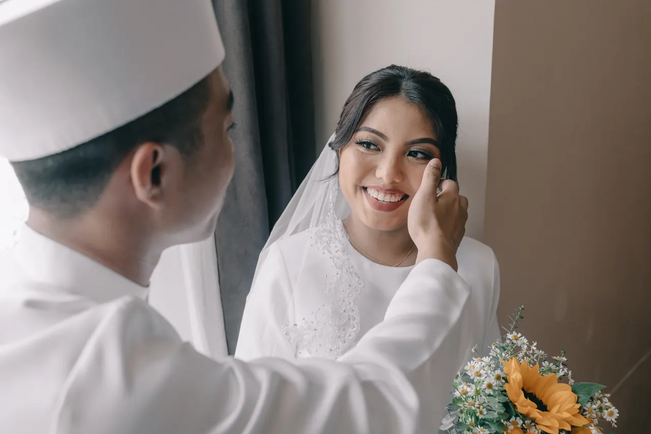 The groom brushes the bride’s cheek; she beams.