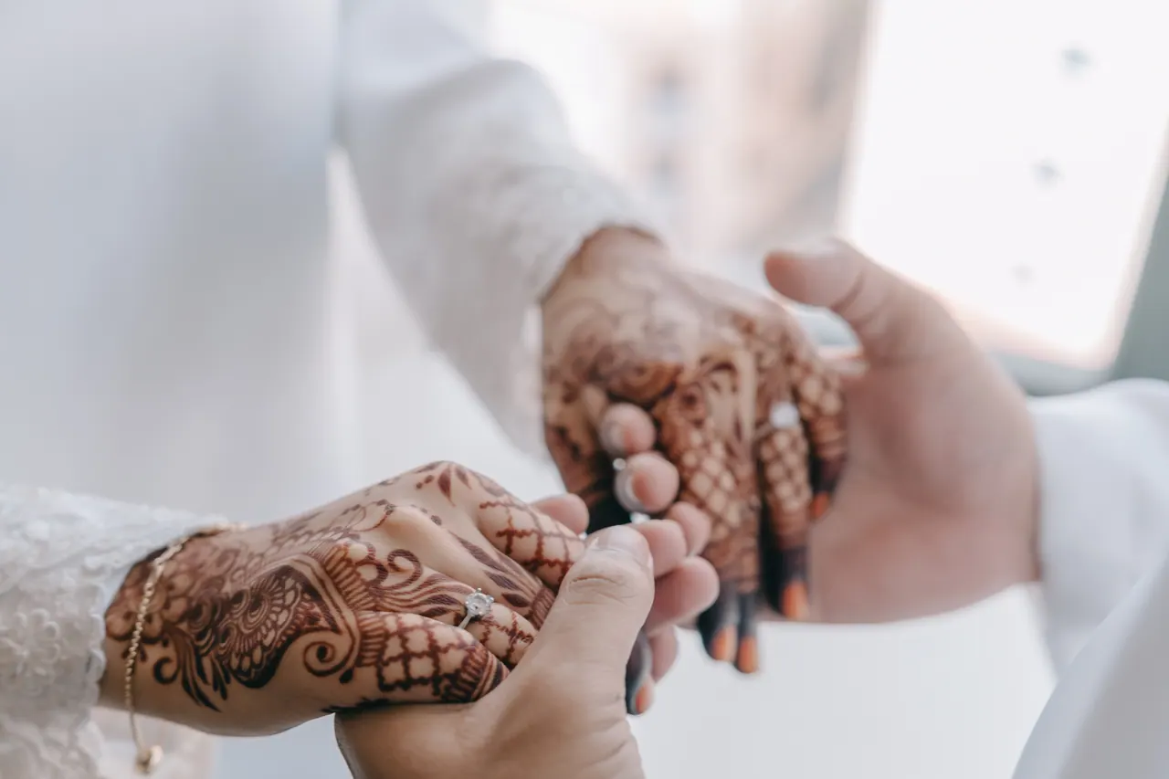 The groom takes the bride’s hennaed hands.