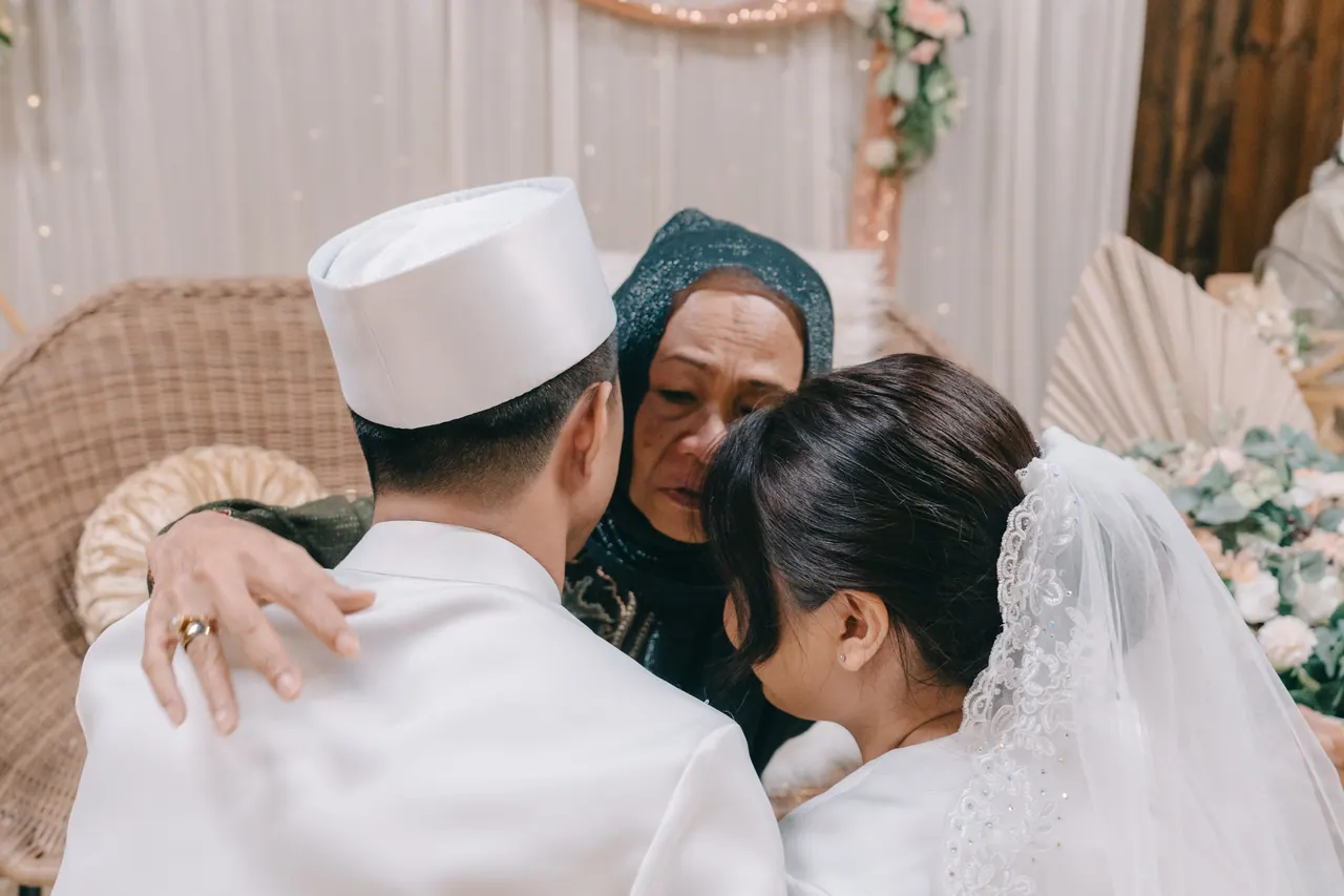 An older woman embraces the couple.