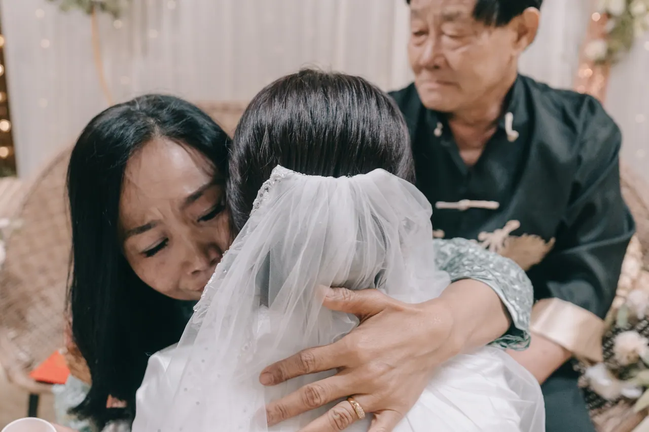 A woman holds the bride in a long embrace.