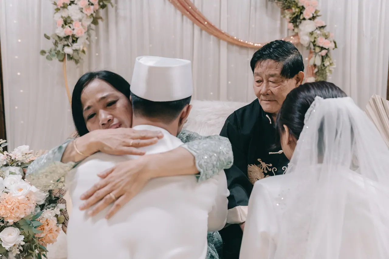 The groom embraces an older woman while an older man looks on.