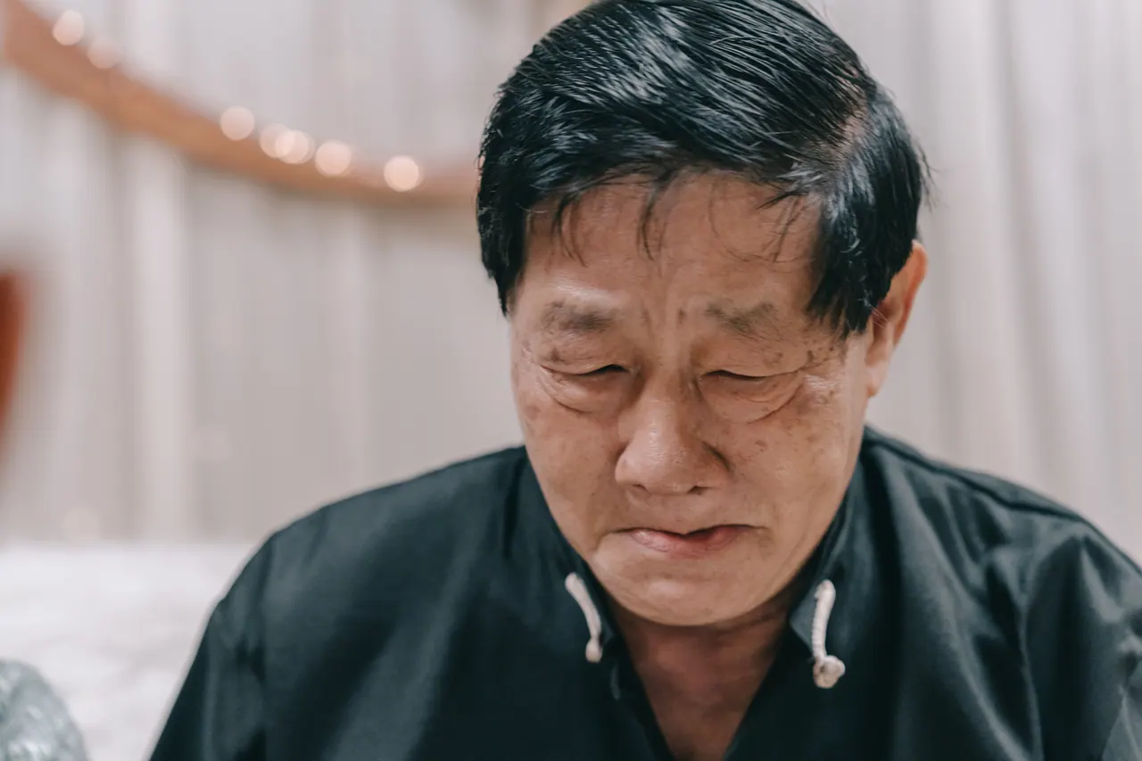 An older man in black, eyes full of tears.