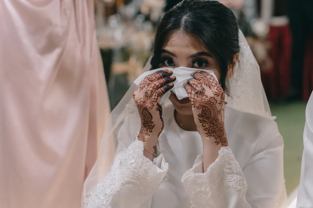 The bride wipes her eyes with a tissue.
