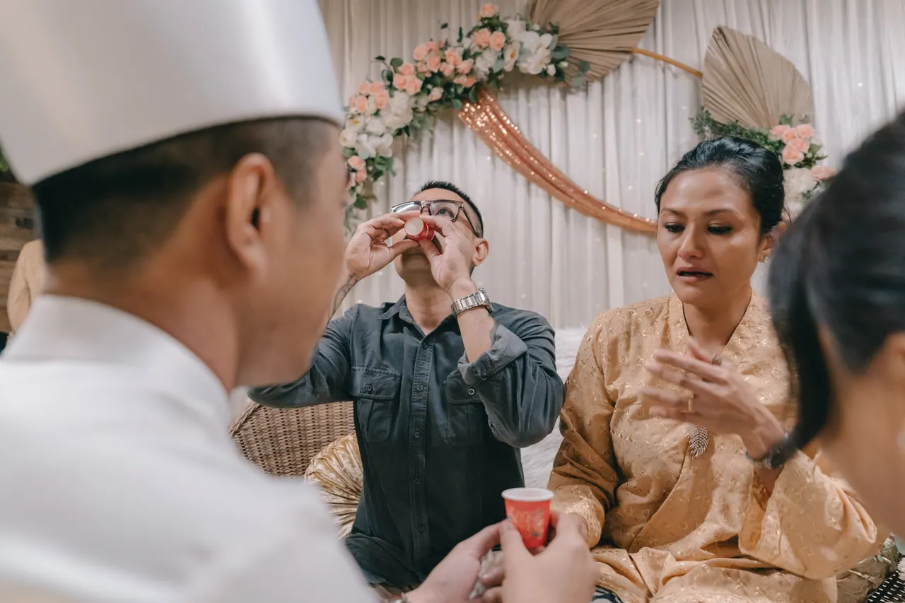 An older couple sip tea as the groom looks on.
