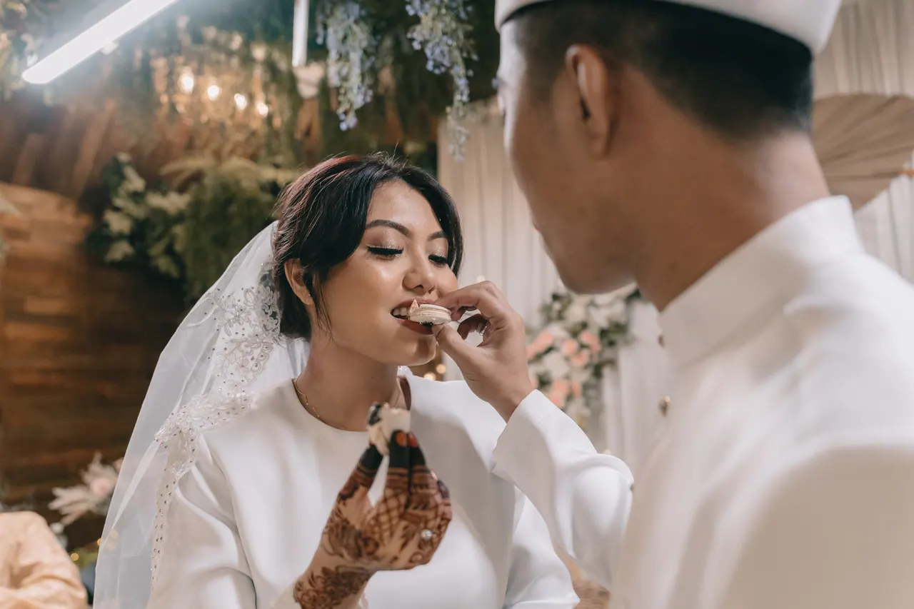 The groom feeds the bride a bite of cake.