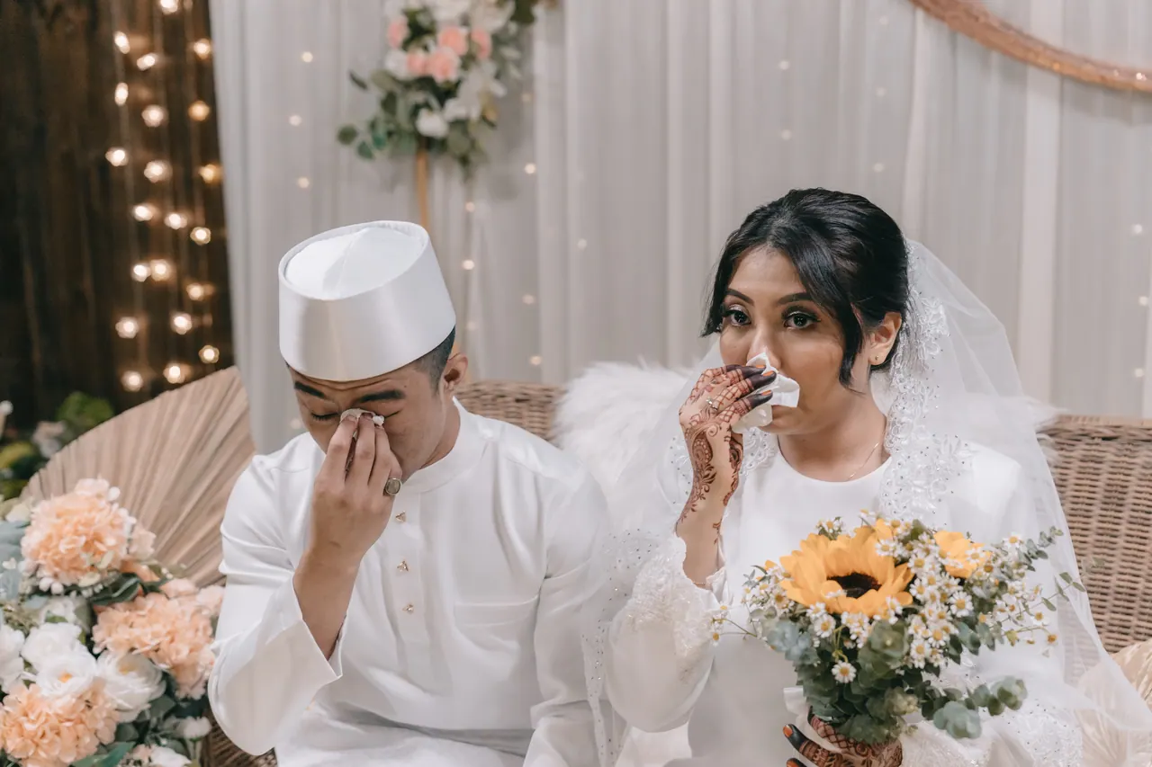 The couple wipe their eyes on the dais.