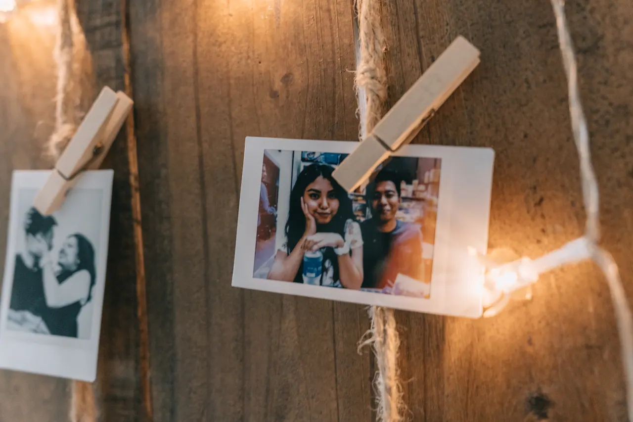 Instant photos of the couple pinned to a wooden board with string lights.