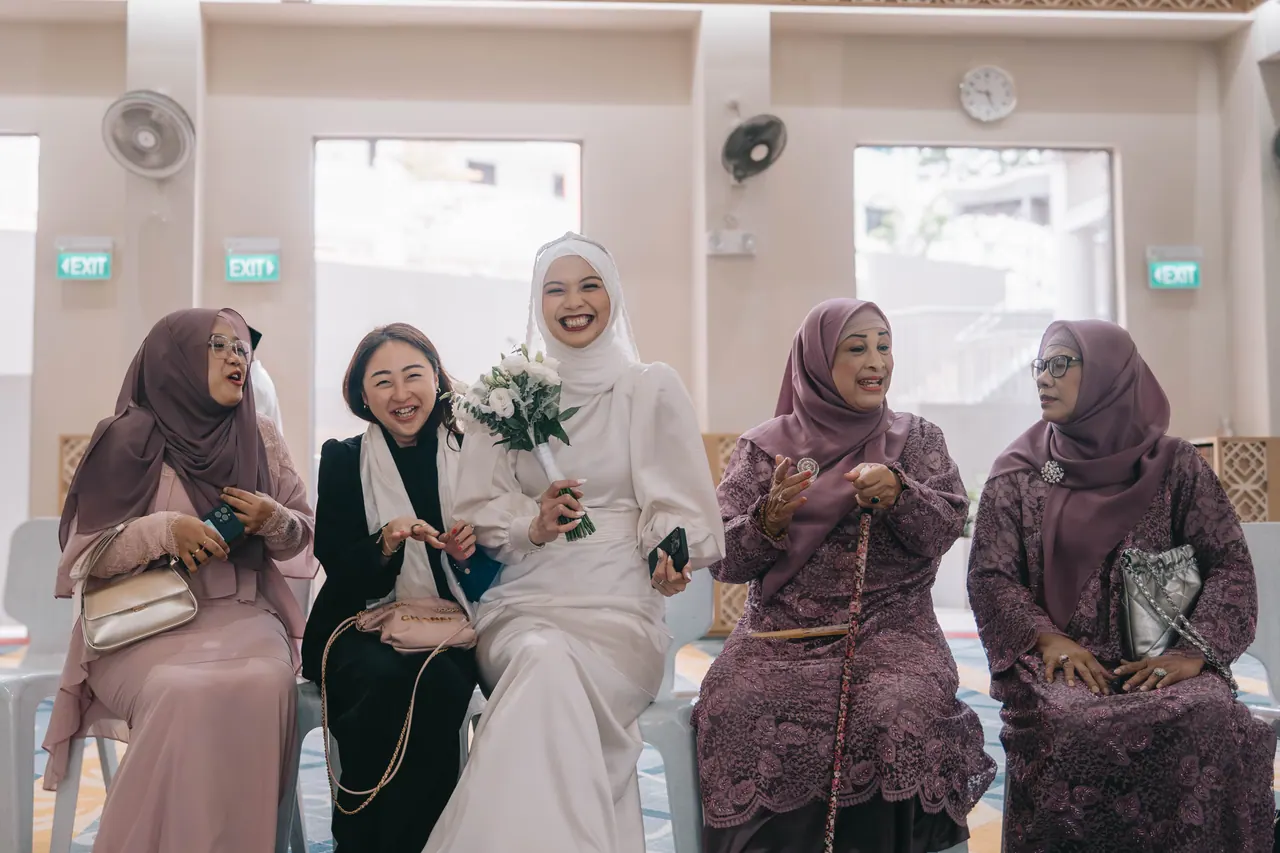 The bride laughs with older women seated beside her.