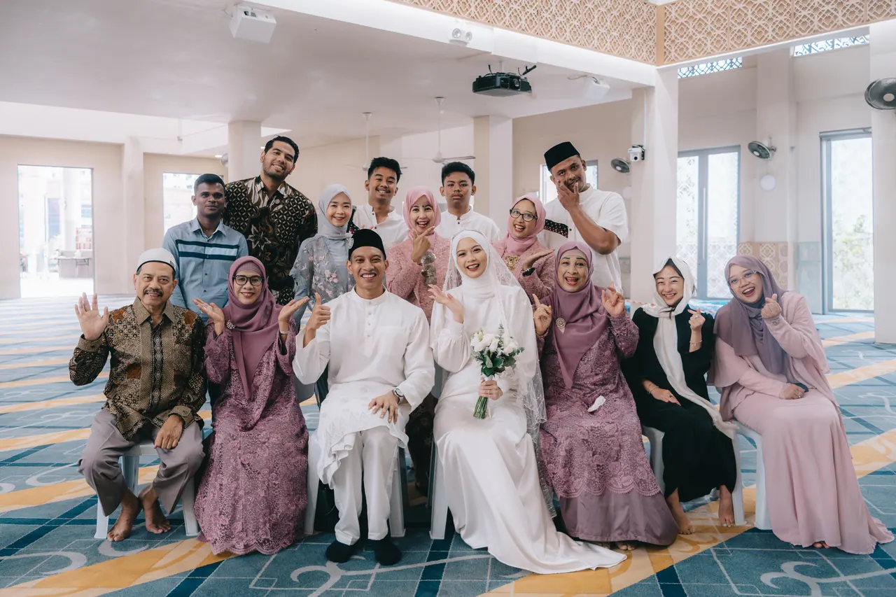 The couple with their family, everyone smiling and waving.
