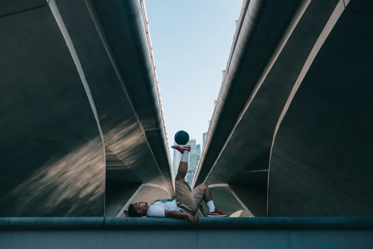 A freestyler beneath a curved concrete bridge.